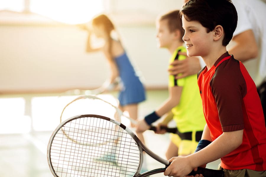 Bilde av tre barn som skal spille tennis, ene gutten er i fokus - Råde IL - Idrettslag