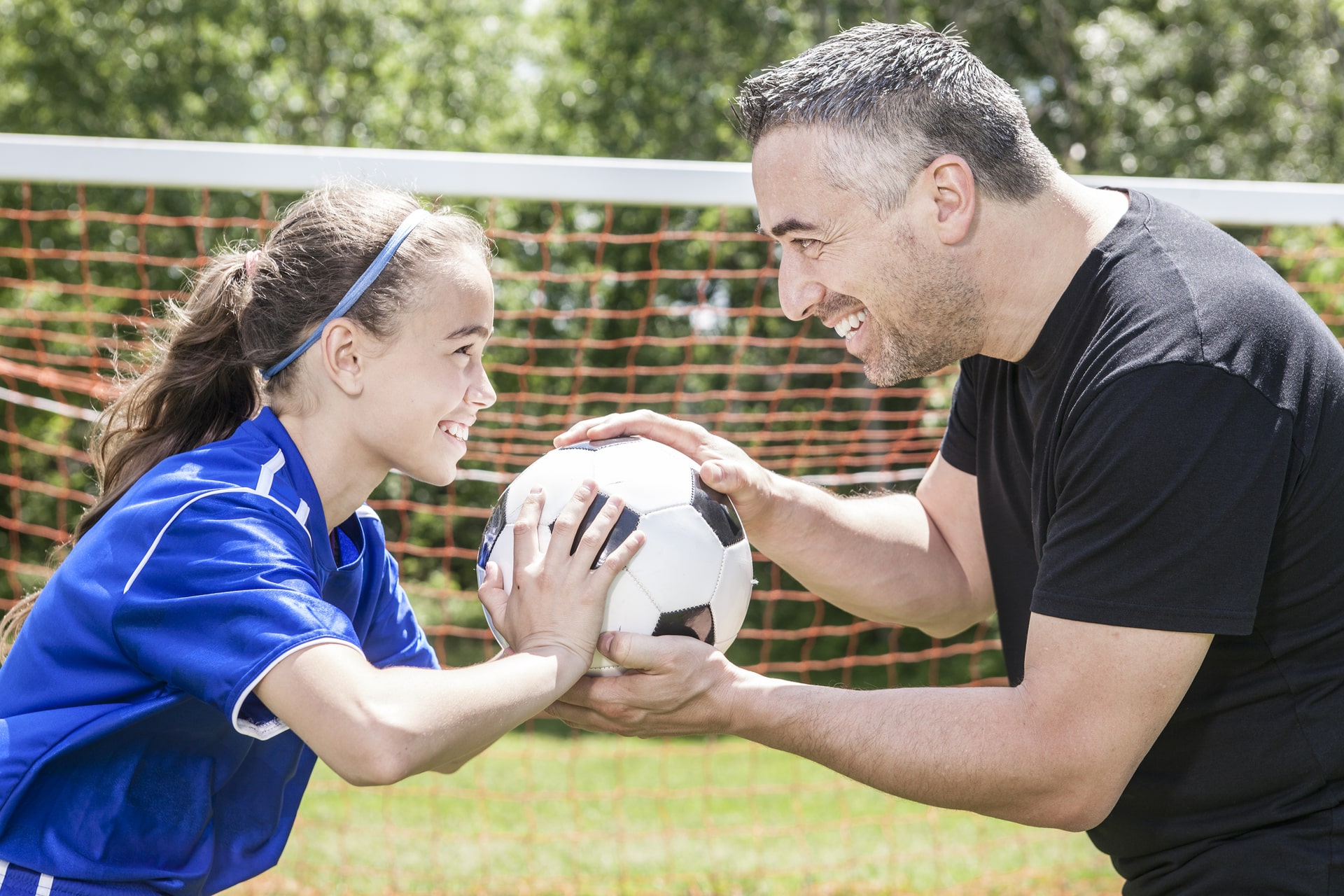 Bilde av en far og datter som holder på en fotball og smiler mot hverandre - Råde IL - Idrettslag